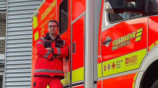 Foto zum Thema Ausbildung zum Notfallsanitäter: Zu sehen ist Tim, einen Notfallsanitäter aus Wuppertal, vor dem Rettungswagen.