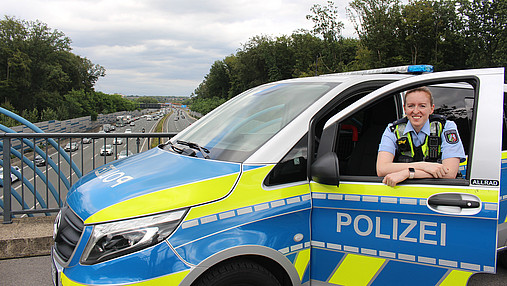 Foto zum Thema "Wie wird man Polizist*in": Zu sehen ist Svenja, die in der Tür des Streifenwagens steht.