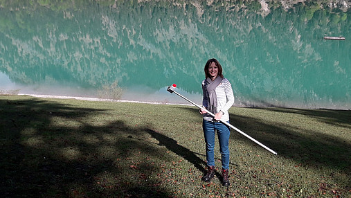 Foto zum Thema Ausbildung zum Hygienekontrolleur: Zu sehen ist Veronika, die für das Gesundheitsamt arbeitet. Sie hält ein Gerät in der Hand, mit dem sie die Wasserqualität im bayerischen Sylvensteinspeicher prüft.