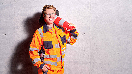 Foto zum Thema "Ausbildung zum Straßenwärter": Zu sehen ist Sandy, die Einblicke in den Job gibt. Sie trägt orangefarbige Sicherheitskleidung. 